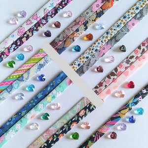 May include: Assortment of colorful fabric strips with various patterns, including floral, geometric, and abstract designs. The strips are arranged in a diagonal pattern and adorned with small, iridescent glass beads.