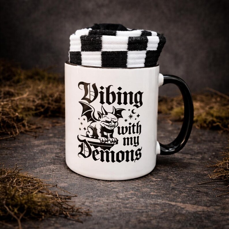 Gothic mug and socks gift set featuring a bold “Vibing with my demons” design and black and white checkered socks presented inside the mug.