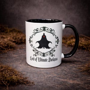 White ceramic two-tone mug featuring “Lord of Ultimate Darkness” design with bold gothic artwork. Styled on a natural stone background with a dark aesthetic. Ideal for gothic gifts, alternative decor, and matching couple mug sets.