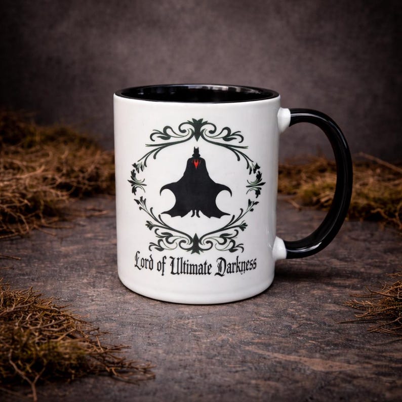 White ceramic two-tone mug featuring “Lord of Ultimate Darkness” design with bold gothic artwork. Styled on a natural stone background with a dark aesthetic. Ideal for gothic gifts, alternative decor, and matching couple mug sets.