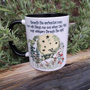Side view of an enchanting moon-gazing hare ceramic mug, featuring a mystical night scene with trees, wildflowers, and an owl in flight. The black and white two-tone finish adds elegance, making it a great gift for spiritual coffee lovers and those who adore magical aesthetics.