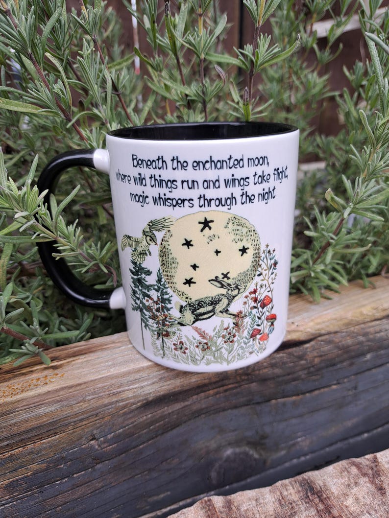 Side view of an enchanting moon-gazing hare ceramic mug, featuring a mystical night scene with trees, wildflowers, and an owl in flight. The black and white two-tone finish adds elegance, making it a great gift for spiritual coffee lovers and those who adore magical aesthetics.