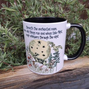 Back view of a nature-inspired ceramic coffee mug showcasing a detailed hare illustration under an enchanted moonlit sky. The intricate forest elements and charming quote make it a perfect addition to witchy home decor, ideal for meditation or daily coffee rituals.
