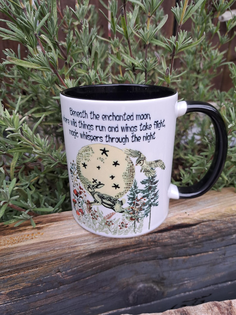Back view of a nature-inspired ceramic coffee mug showcasing a detailed hare illustration under an enchanted moonlit sky. The intricate forest elements and charming quote make it a perfect addition to witchy home decor, ideal for meditation or daily coffee rituals.