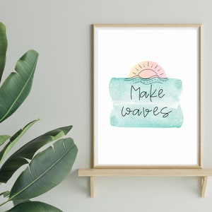 May include: A framed print with a watercolor background of a sunset over the ocean. The text "Make waves" is written in black cursive on the print.