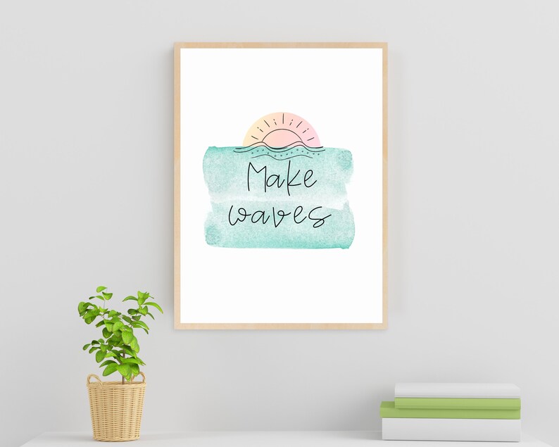 May include: A framed print with a watercolor background in shades of blue and green. The print features a simple line drawing of a sun setting over a wavy line, with the text "Make waves" written below.