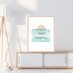 May include: A framed print with a watercolor background of a sunset over the ocean. The text "Make waves" is written in black cursive script.