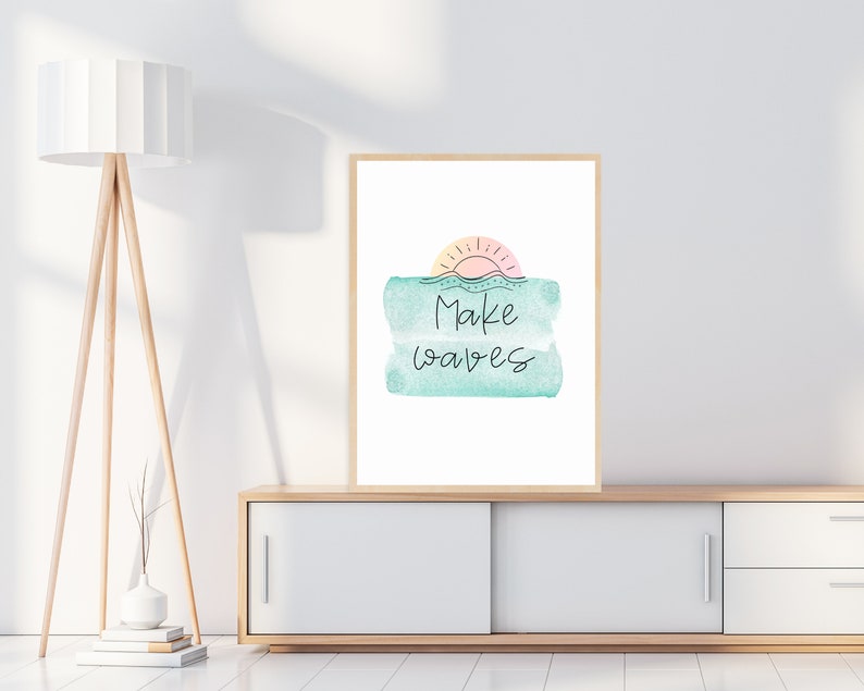 May include: A framed print with a watercolor background of a sunset over the ocean. The text "Make waves" is written in black cursive script.