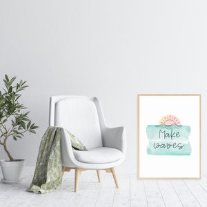 May include: A framed print with a watercolor design of a sunset over the ocean. The text "Make waves" is written in black cursive script.