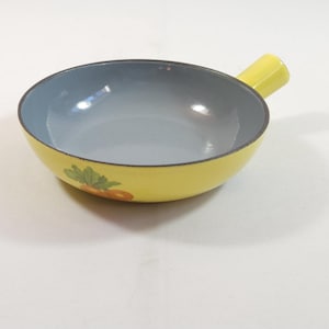 Op de afbeelding: Een gele emaille fonduepot met een blauw interieur en een ananasontwerp. De pot heeft een enkele handgreep.
