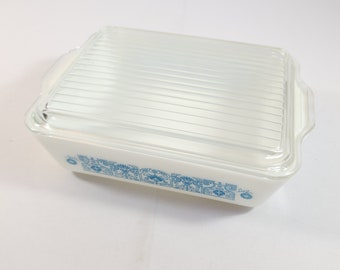 Op de afbeelding: Witte rechthoekige ovenschaal met een doorzichtig glazen deksel. De schaal heeft een blauw en wit bloemmotief rond de rand.