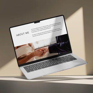 May include: A silver laptop computer with a white screen displaying a website with the text "ABOUT ME" and a photo of a couple exchanging rings. The laptop is floating in the air above a light brown surface.