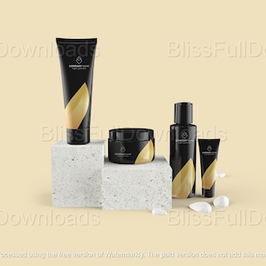 May include: A collection of black cosmetic product containers with gold leaf accents, including a tube, jar, bottle, and small tube, arranged on textured white blocks. The containers have the text "COMPANY NAME" and "tagline goes here".