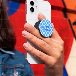 May include: A white smartphone with a black camera lens and a blue and white popsocket with the text "POPSOCKERS mockup" attached to the back.