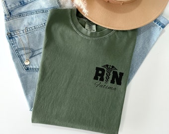 May include: A green t-shirt with a black graphic of a medical caduceus and the letters "RN" with the name "Fatima" underneath.