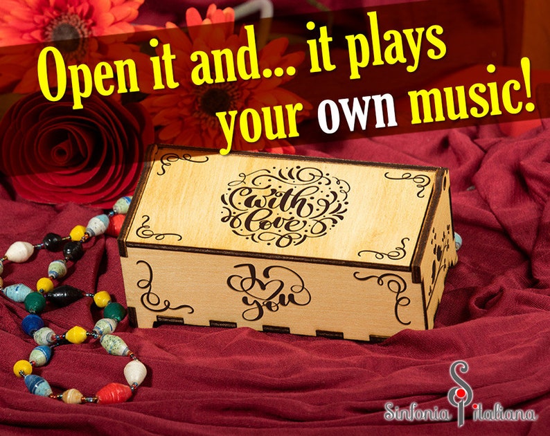 May include: A wooden music box with a hinged lid. The lid is engraved with the words "With Love" and "I Love You". The box is sitting on a red fabric surface.
