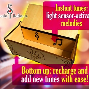 May include: A wooden music box with a light sensor that plays melodies when exposed to light. The box is open, revealing a small music note button and the words "Sinfonia Italiana" on the lid. The text "Instant tunes: light sensor-activated melodies" is written in a pink box above the music box. The text "Bottom up: recharge and add new tunes with ease!" is written in a pink box below the music box.