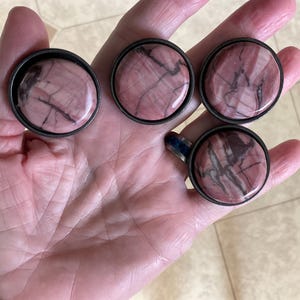 May include: Five round, pink and brown, marbled stone drawer pulls with silver metal settings.