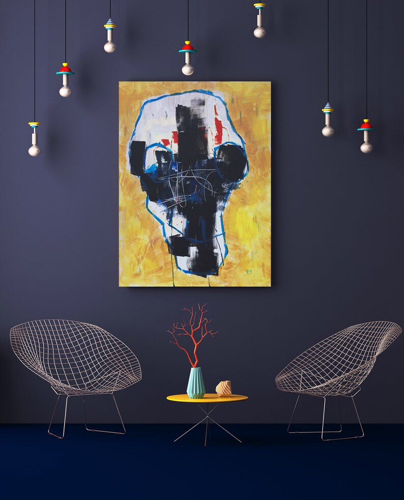 May include: An abstract painting with a yellow background and black and white shapes hangs on a dark blue wall. Two wire chairs and a small yellow table with a vase and coral-colored branches are in front of the wall. Decorative hanging lights.