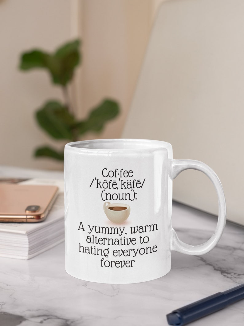 May include: White ceramic coffee mug with a handle. The mug features the word "Coffee" with phonetic pronunciation and the phrase "A yummy, warm alternative to hating everyone forever."