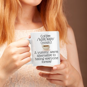 May include: White ceramic coffee mug with the text "Coffee /'k&ocirc;fe, k&auml;fe/ (noun): A yummy, warm alternative to hating everyone forever." The mug has a handle and a small illustration of a coffee cup.