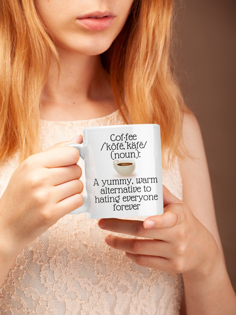 May include: White ceramic coffee mug with the text "Coffee /'k&ocirc;fe, k&auml;fe/ (noun): A yummy, warm alternative to hating everyone forever." The mug has a handle and a small illustration of a coffee cup.