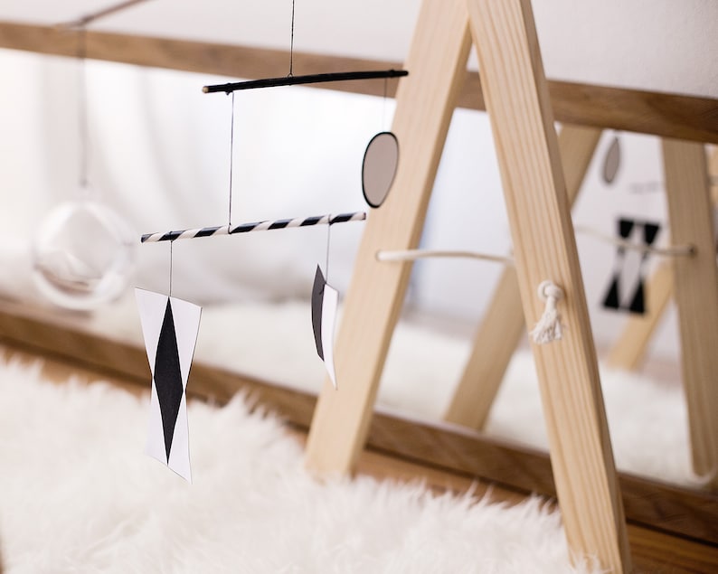 The Montessori Munari mobile in front of a mirror, hanging on a mobile stand.