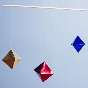 The DIY Montessori Octahedron baby mobile in front of a blue background.