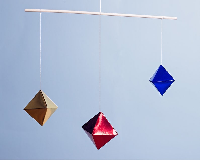 The DIY Montessori Octahedron baby mobile in front of a blue background.