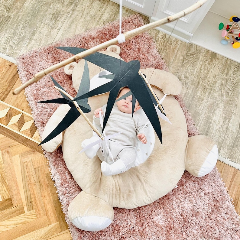 Baby gazing at the slowly moving swallow figures, developing early visual tracking and concentration.