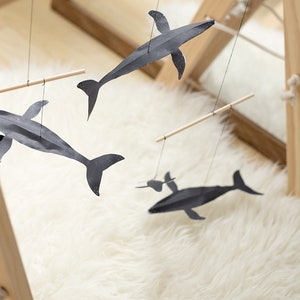 DIY Montessori Whale Mobile with black and white animal shapes hanging above baby play area or changing table