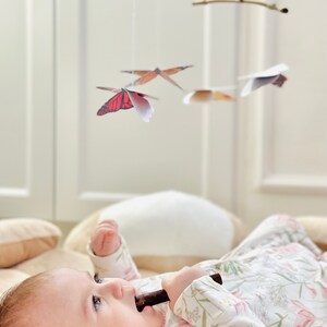 A baby girl is looking at the DIY Montessori Butterfly Mobile.