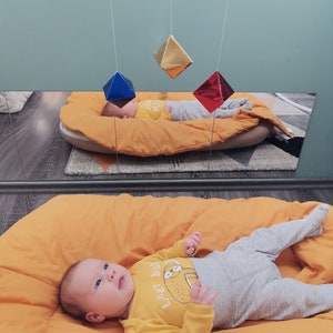 A baby girl in a room, looking at the DIY Montessori Octahedron baby mobile