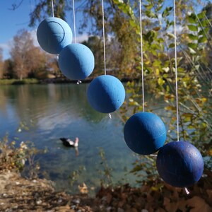 The DIY Montessori Gobbi mobile kit for newborn visual development, hanging outside in front of a lake with a duck.