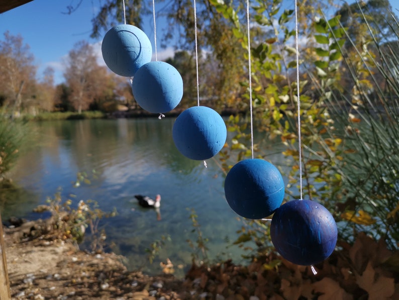 The DIY Montessori Gobbi mobile kit for newborn visual development, hanging outside in front of a lake with a duck.
