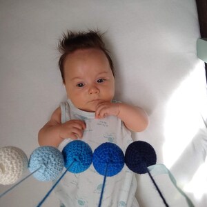 A baby boy is observing the Crocheted Gobbi mobile
