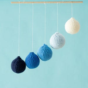 The DIY Montessori crocheted Gobbi with the transparent elastic cord, mobile in front of a blue background.