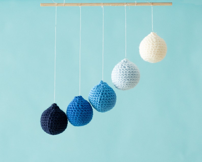 The DIY Montessori crocheted Gobbi with the transparent elastic cord, mobile in front of a blue background.