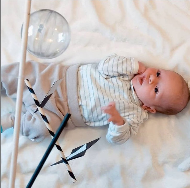 A baby boy is looking at the Montessori Munari mobile.