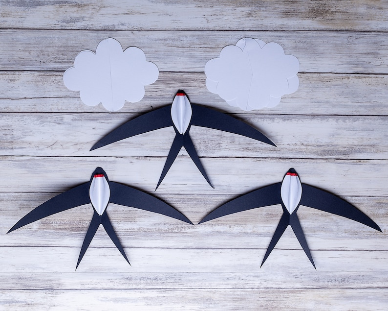 The five elements of the DIY Montessori Swallows Mobile, on a wooden background.