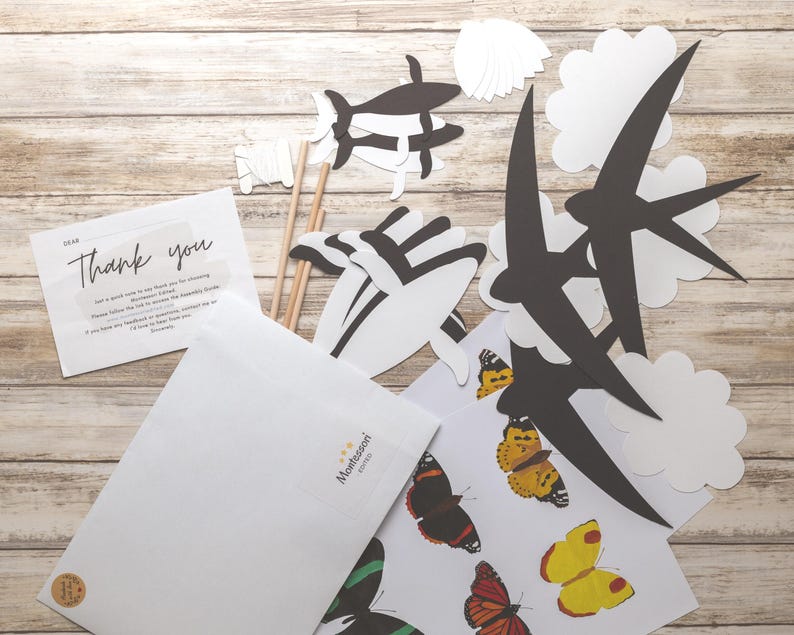 DIY animal mobile kit contents displayed, including templates, dowels, thread, and printed instruction