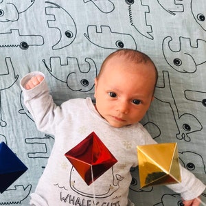 A baby boy is looking at the Montessori Octahedron mobile.