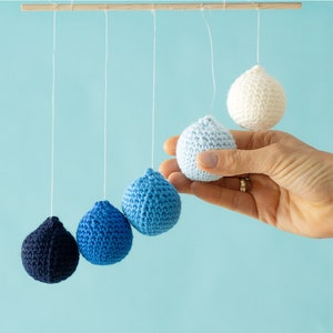 The Crocheted Gobbi mobile in the tactile version, a hand holding a ball for scale