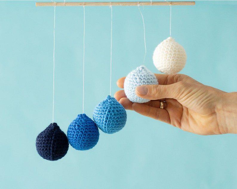 The Crocheted Gobbi mobile in the tactile version, a hand holding a ball for scale