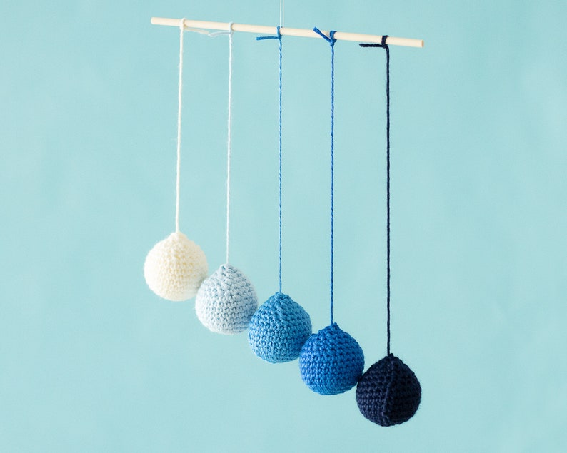 The Montessori Crocheted Gobbi mobile in front of a blue background.