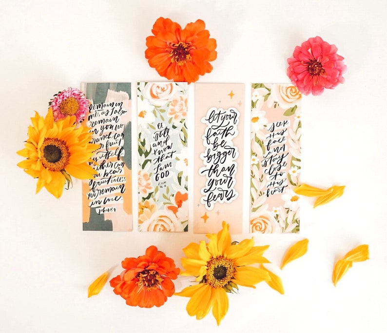 May include: Four floral bookmarks with inspirational quotes. The quotes are "Remain in me, as I also remain in you. If you continue in my word, you will truly be my disciple. John 15:4-7", "It is still and know that I am God. Psalm 46:10", "Let your faith be bigger than your fears", "Seek his face, and stay close to his heart".