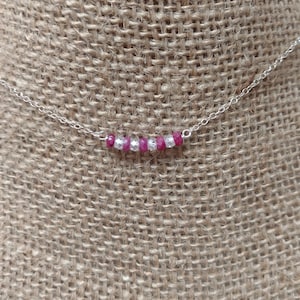May include: A silver chain necklace with a row of alternating pink and clear faceted beads.