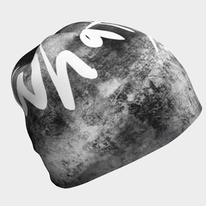 May include: Black and white beanie with a white "what" written on the side. The beanie has a textured, marbled look.