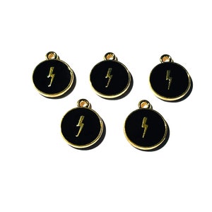 May include: Five gold-coloured metal charms with black enamel and a gold lightning bolt design.