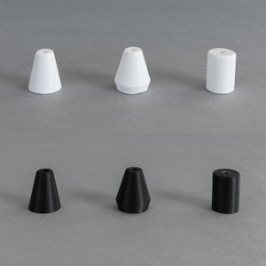 Peut inclure: Six embouts de lampe différents, trois blancs et trois noirs. Les embouts blancs sont en forme de cône, tandis que les embouts noirs sont un mélange de formes coniques et cylindriques.